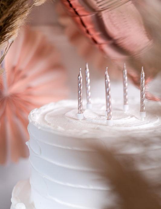 Gros plan des bougies sur un gâteau du 12 bougies d'anniversaire rose gold métallique avec supports