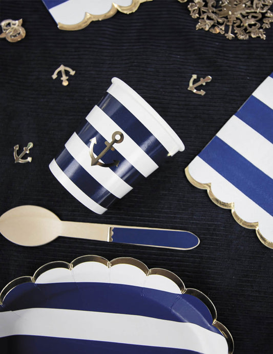Mise en scène de table des serviettes festonnées en papier marinière bleu marine et blanc à bords dorés avec ancre