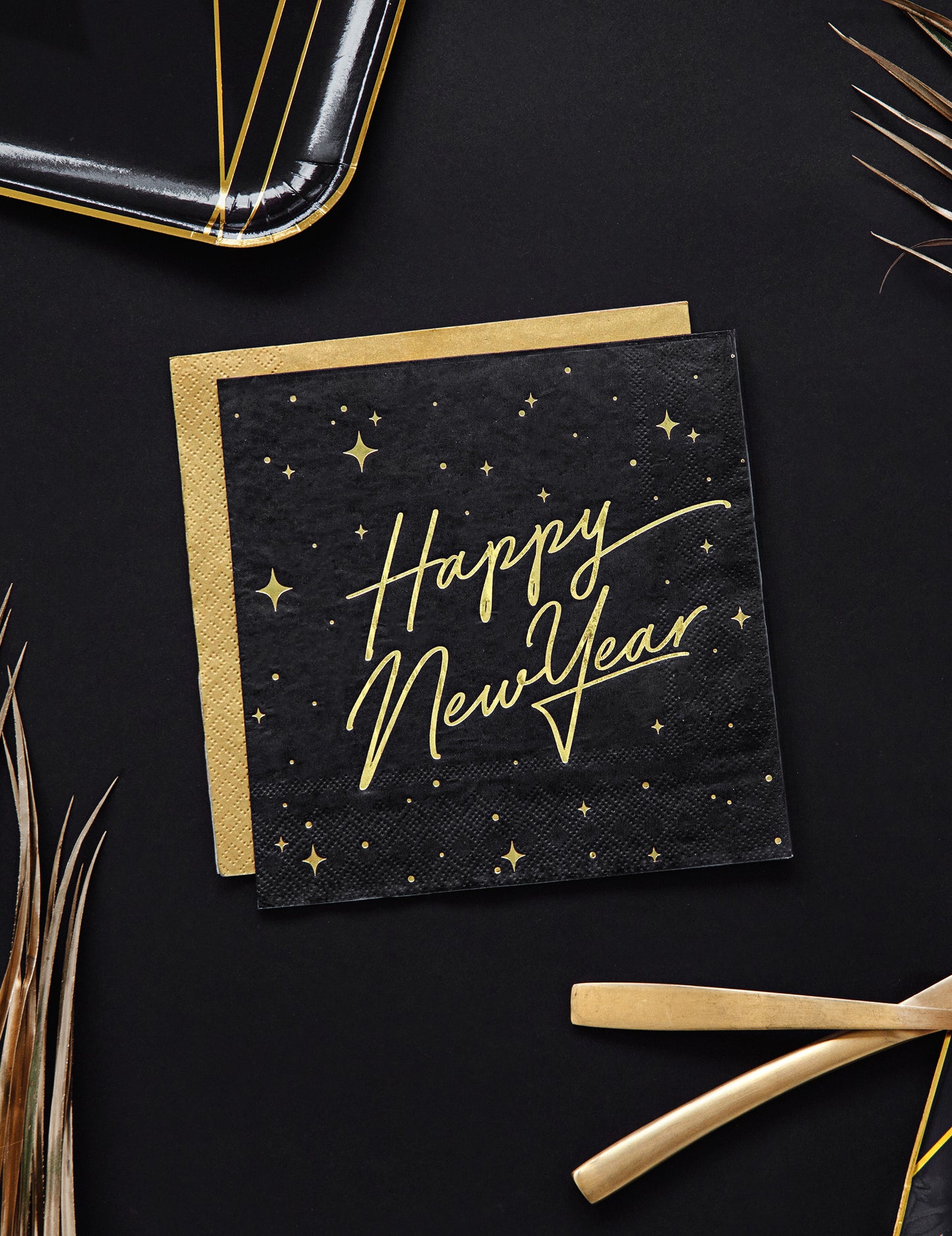 Vue de dessus des serviettes en papier Happy New Year noires et dorées avec décor étoilé