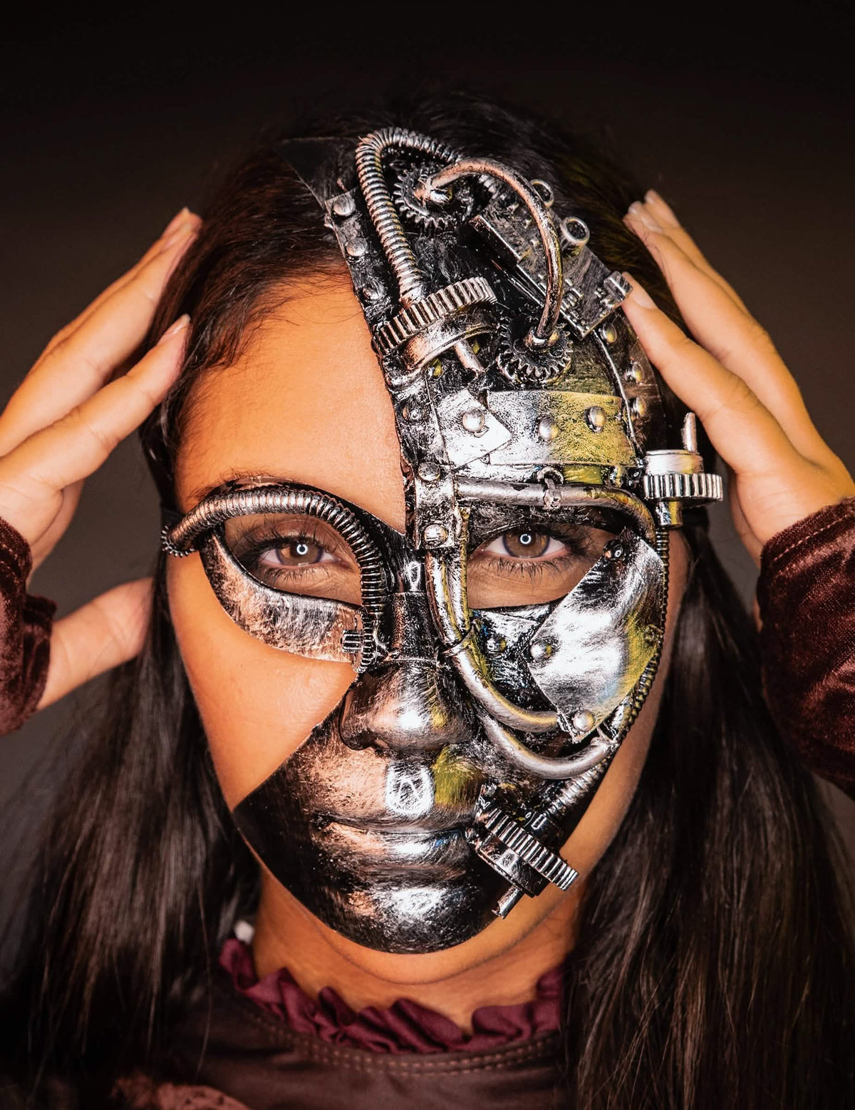Edestäpäin, kädet ohimoilla, steampunk-robottipuolinaamari