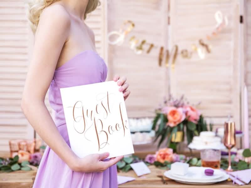 Mise en situation tenue à la main du guest book pour mariage blanc et rose gold