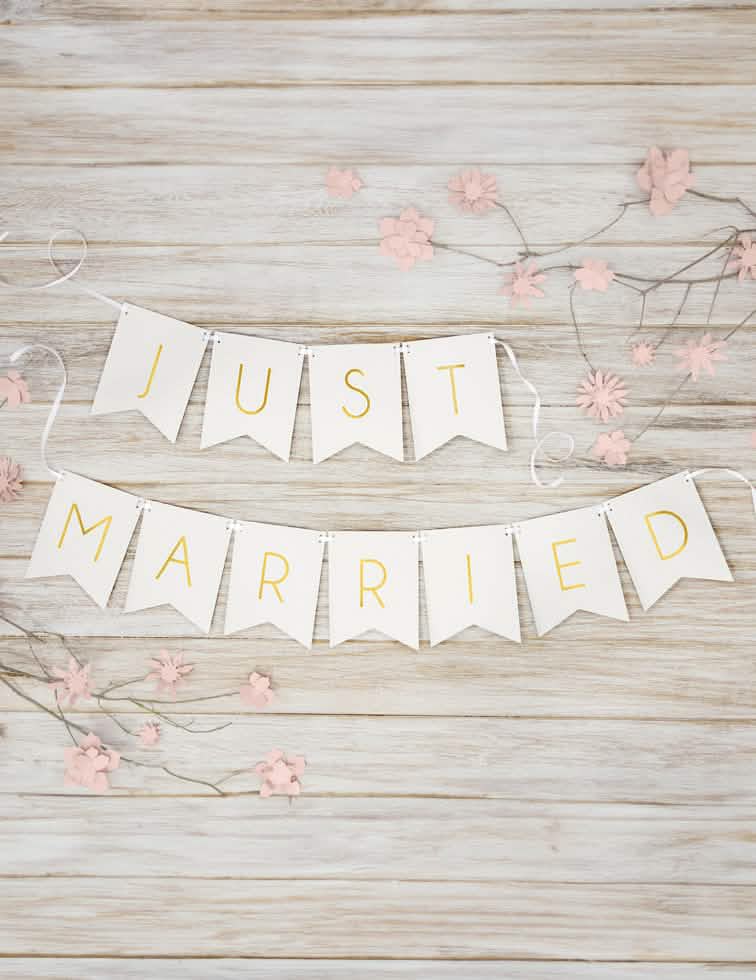 Mise en scène sur fond bois de la guirlande en carton Just Married pour mariage