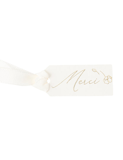 Gros plan sur le ruban et l'écriture dorée des étiquettes merci fleurs pour baptême
