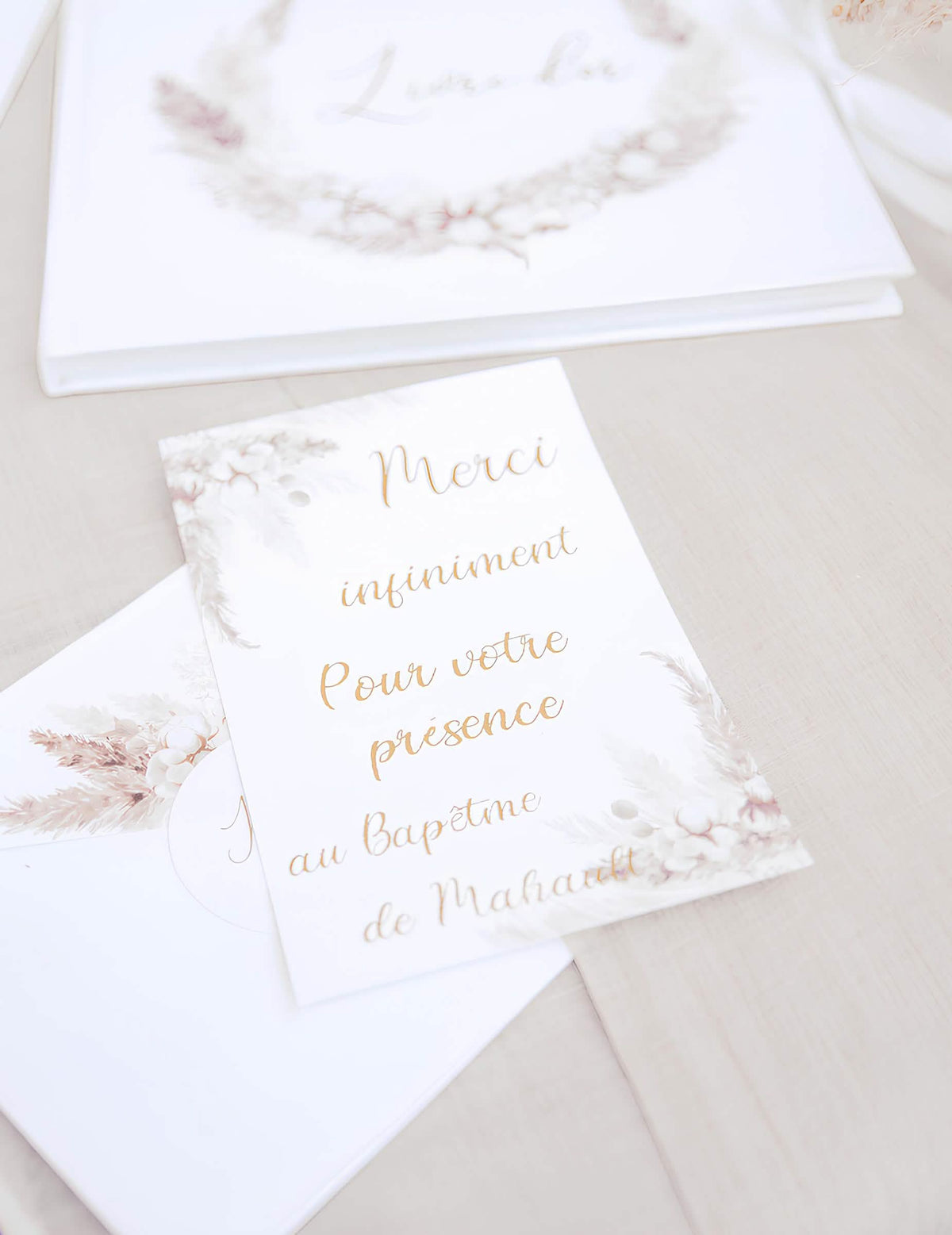 Gros plan sur le texte des invitations avec enveloppes pampas et fleurs de coton