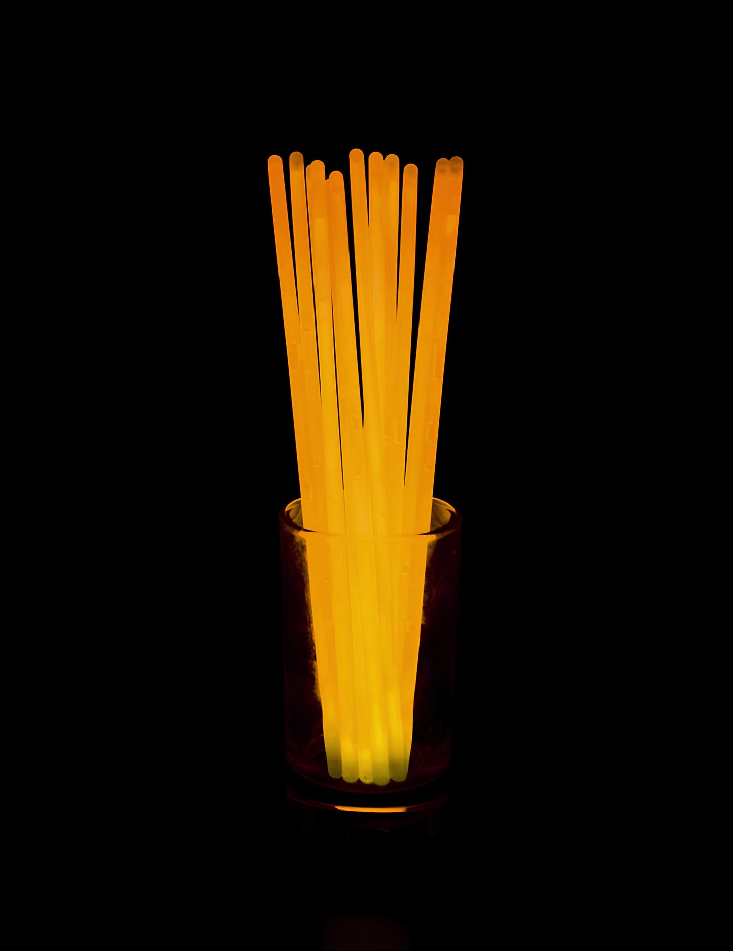Rendu lumineux dans l'obscurité du lot de 100 bracelets phosphorescents pour fête orange
