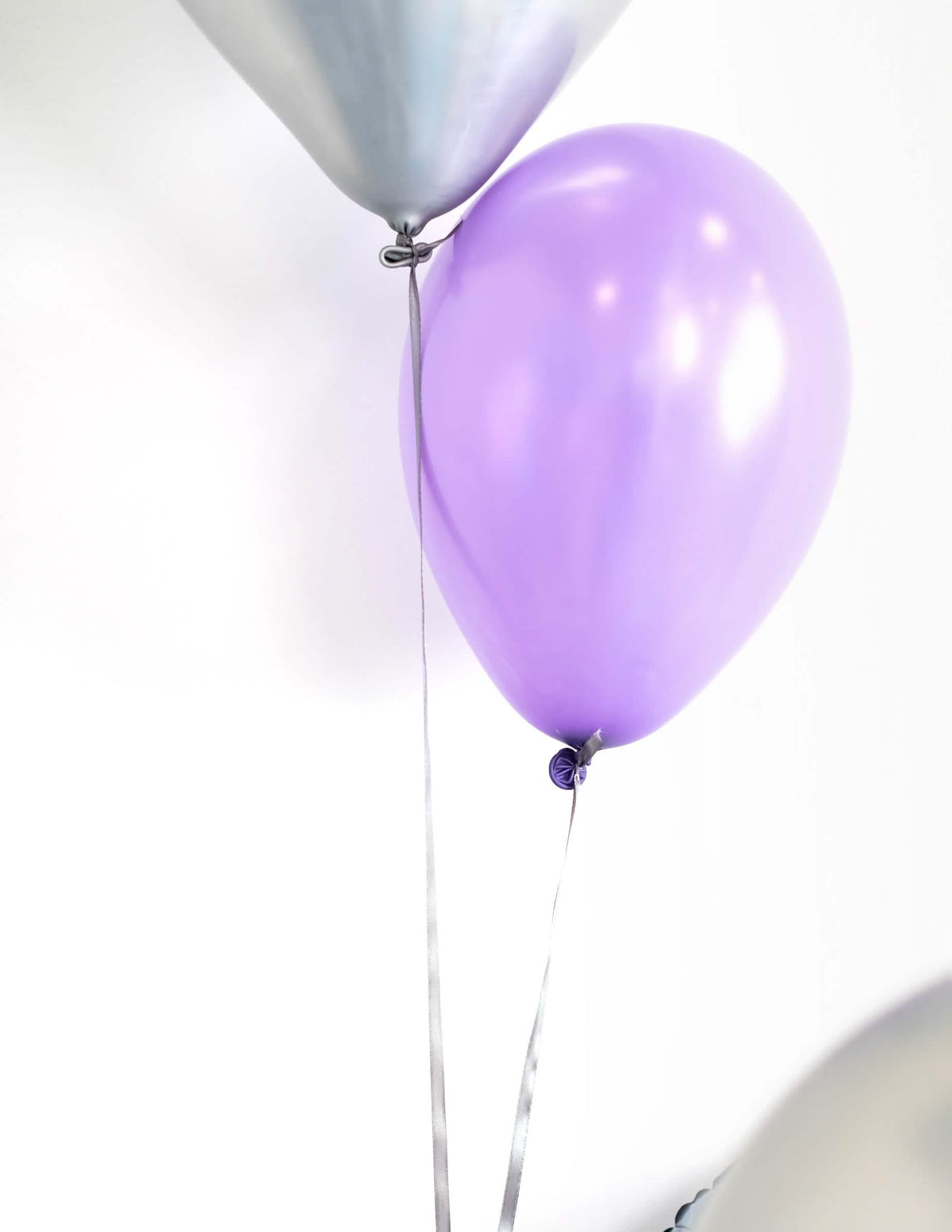 Lähikuva ilmapalloista nauhoilla, juhlan metallisoiduista ilmapalloista koristeluun, lilaa