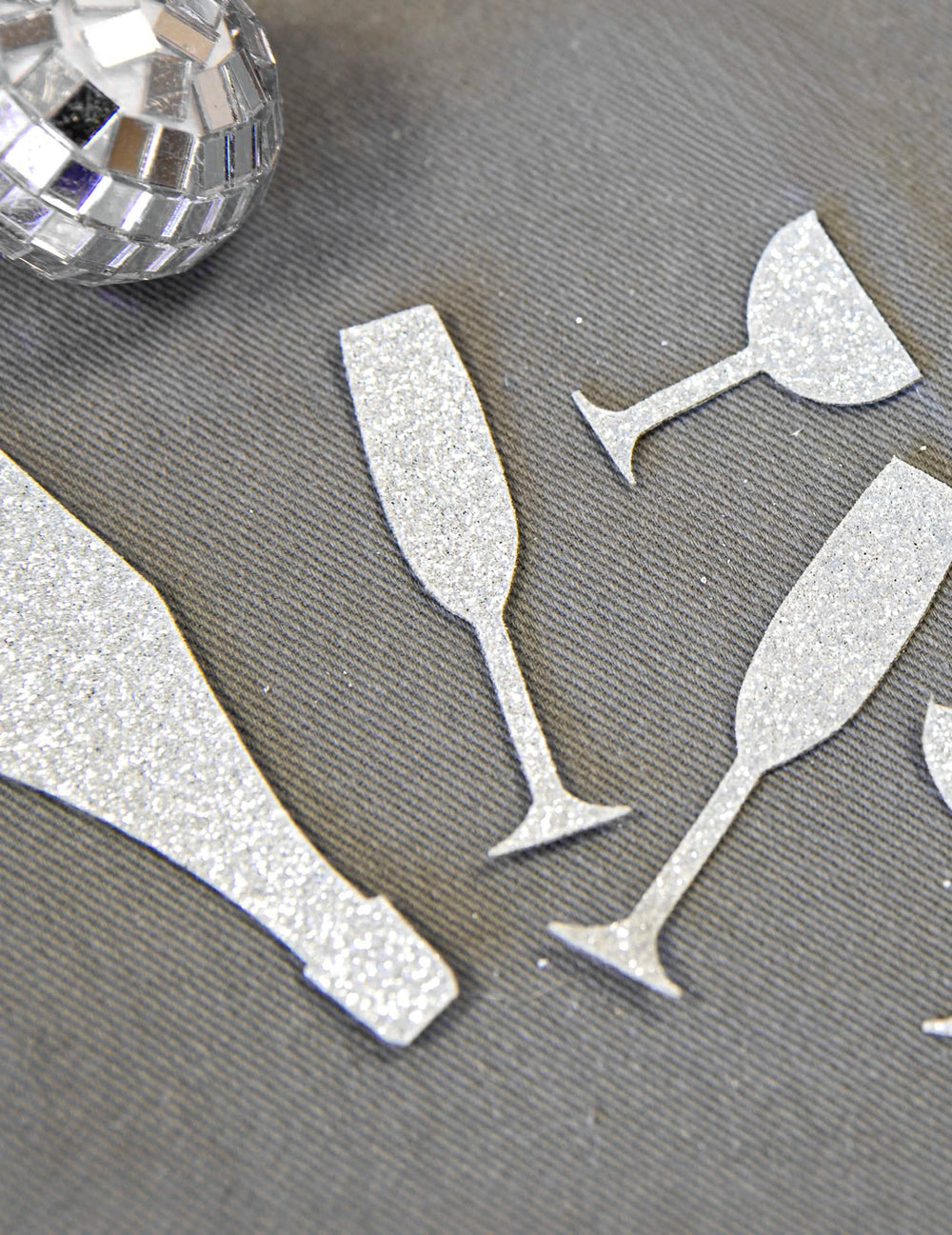 Gros plan sur la texture pailletée des confettis de table champagne argentés coupes et flûtes