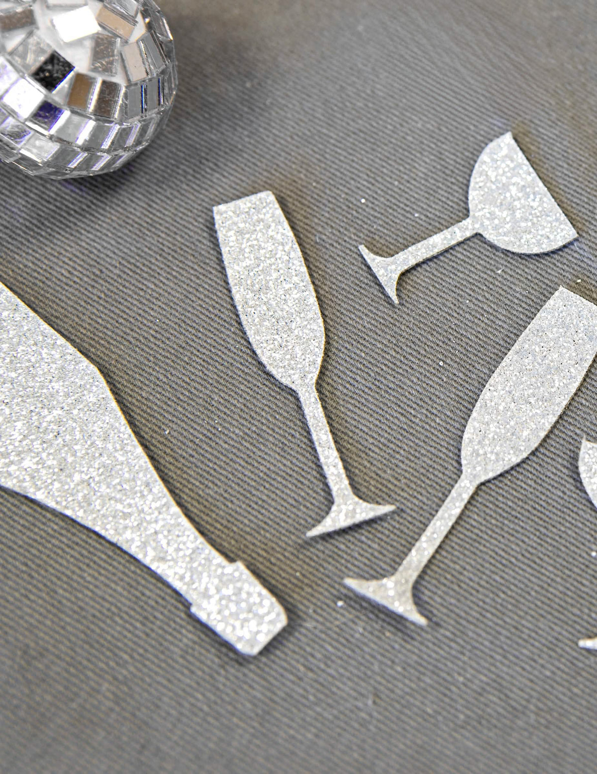 Gros plan sur la texture pailletée des confettis de table champagne argentés coupes et flûtes