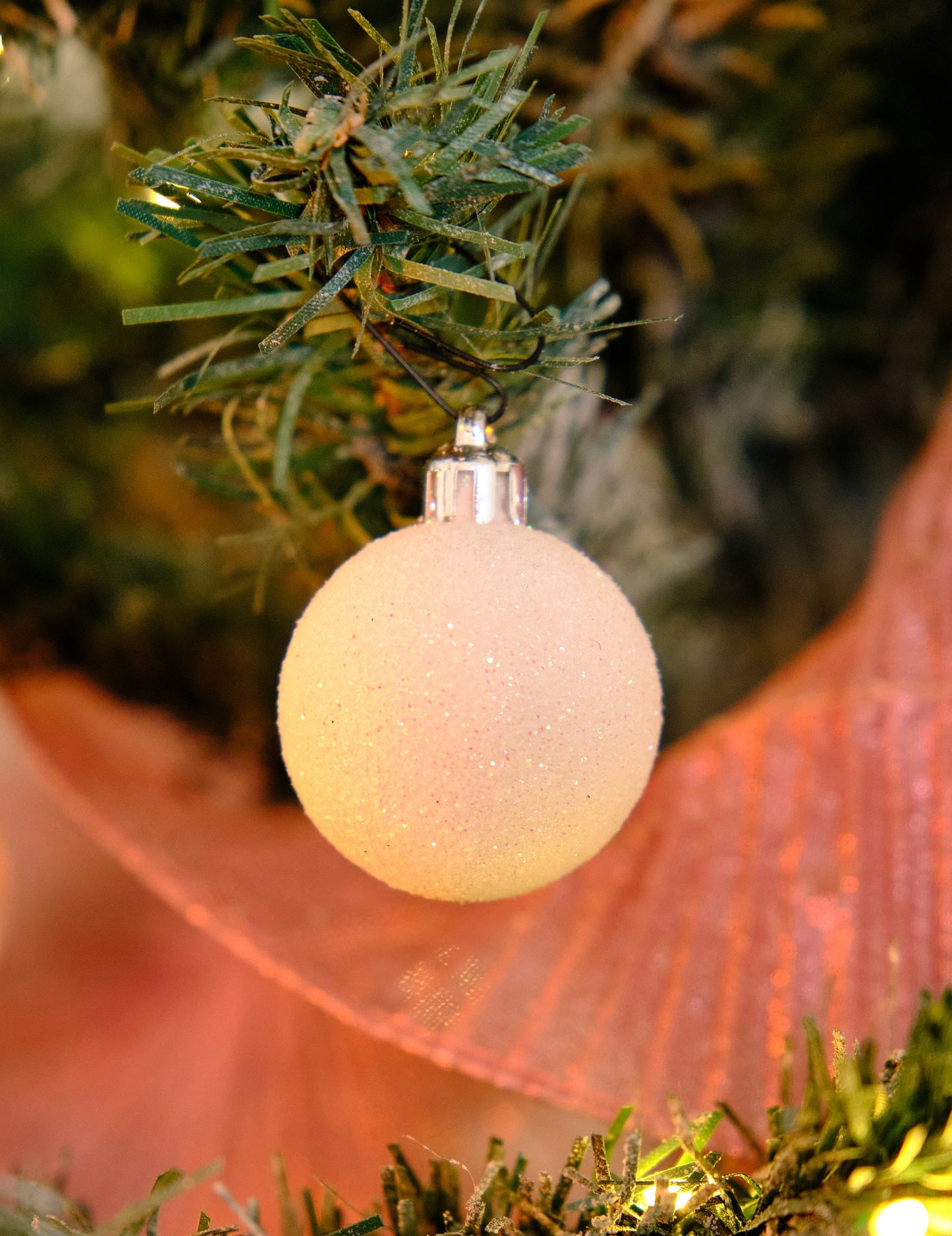 Gros plan d'une boule pailletée du lot de 18 mini boules de Noël blanches pailletées et mates