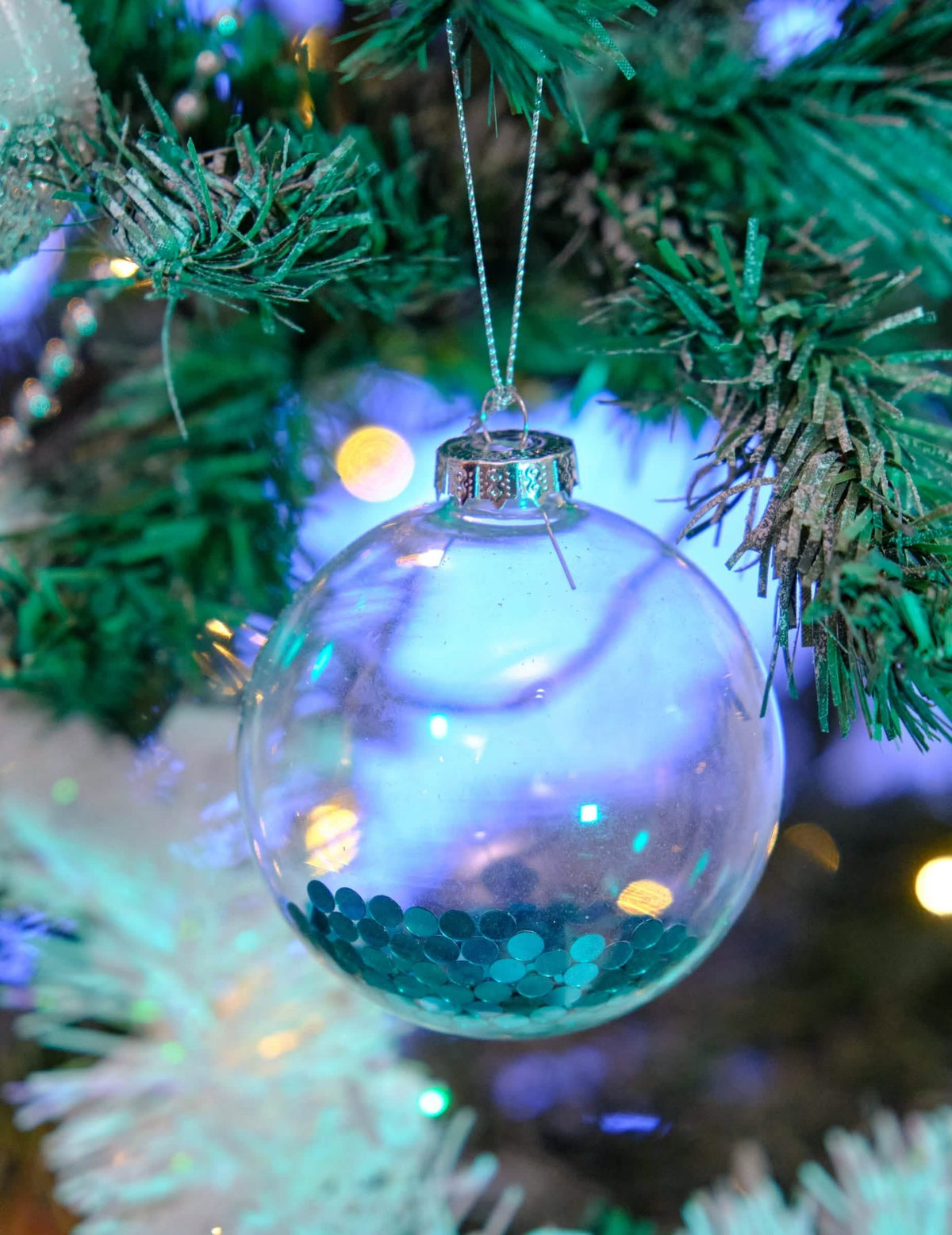 Lähikuva läpinäkyvistä joulukuusen lasipalloista, joissa on sinistä glitteriä