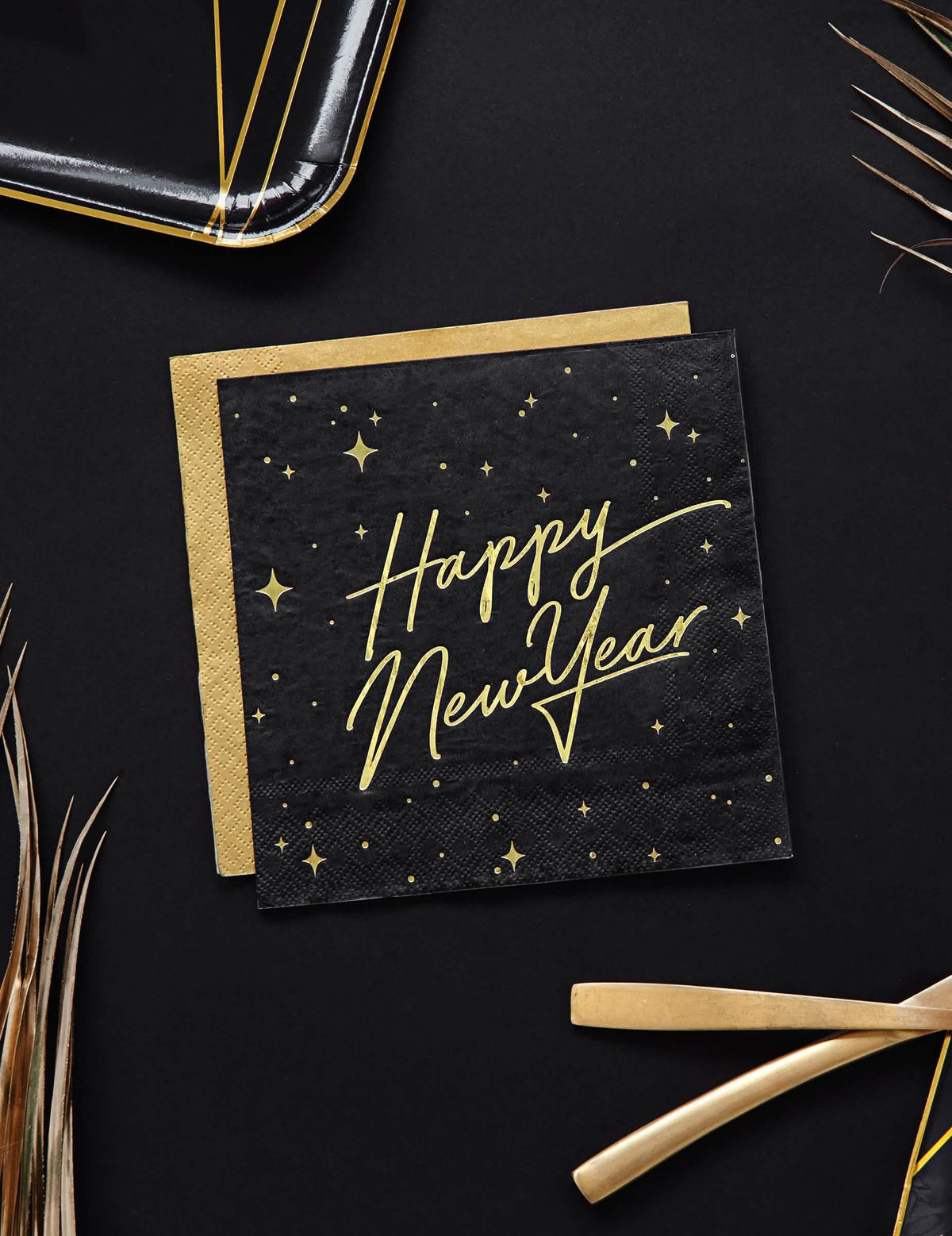 Vue de dessus des serviettes en papier Happy New Year noires et dorées avec décor étoilé