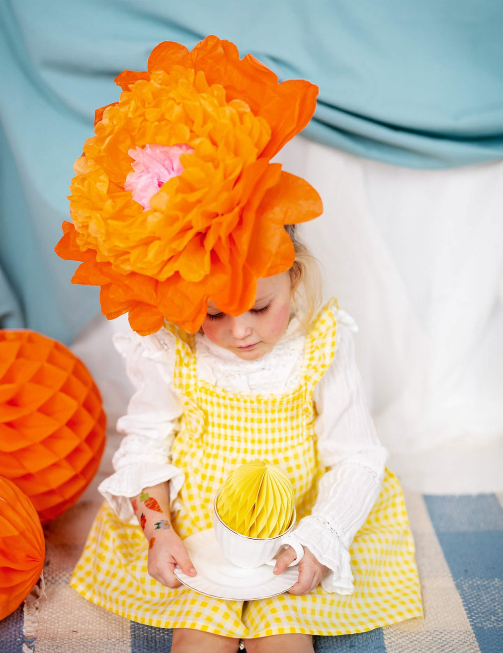Détail de la fleur orange portée sur la tête des fleurs géantes en papier à suspendre rose jaune et orange