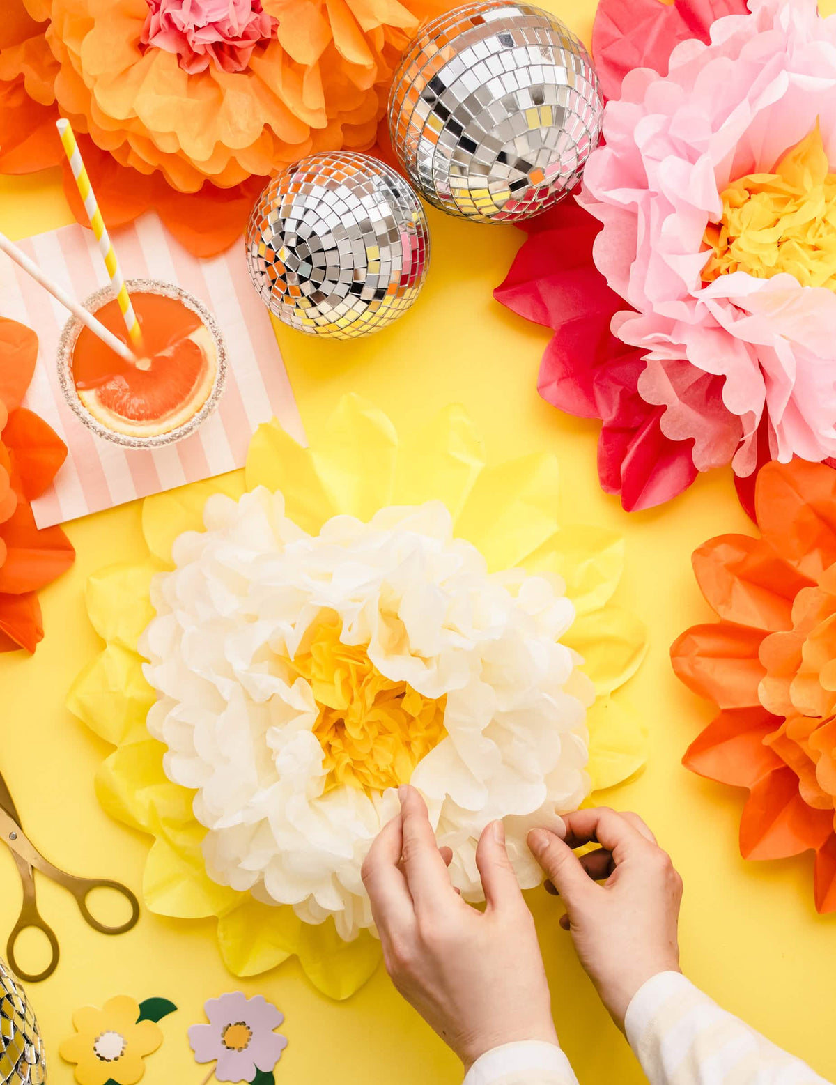 Détail de l'assemblage manuel des fleurs géantes en papier à suspendre rose jaune et orange