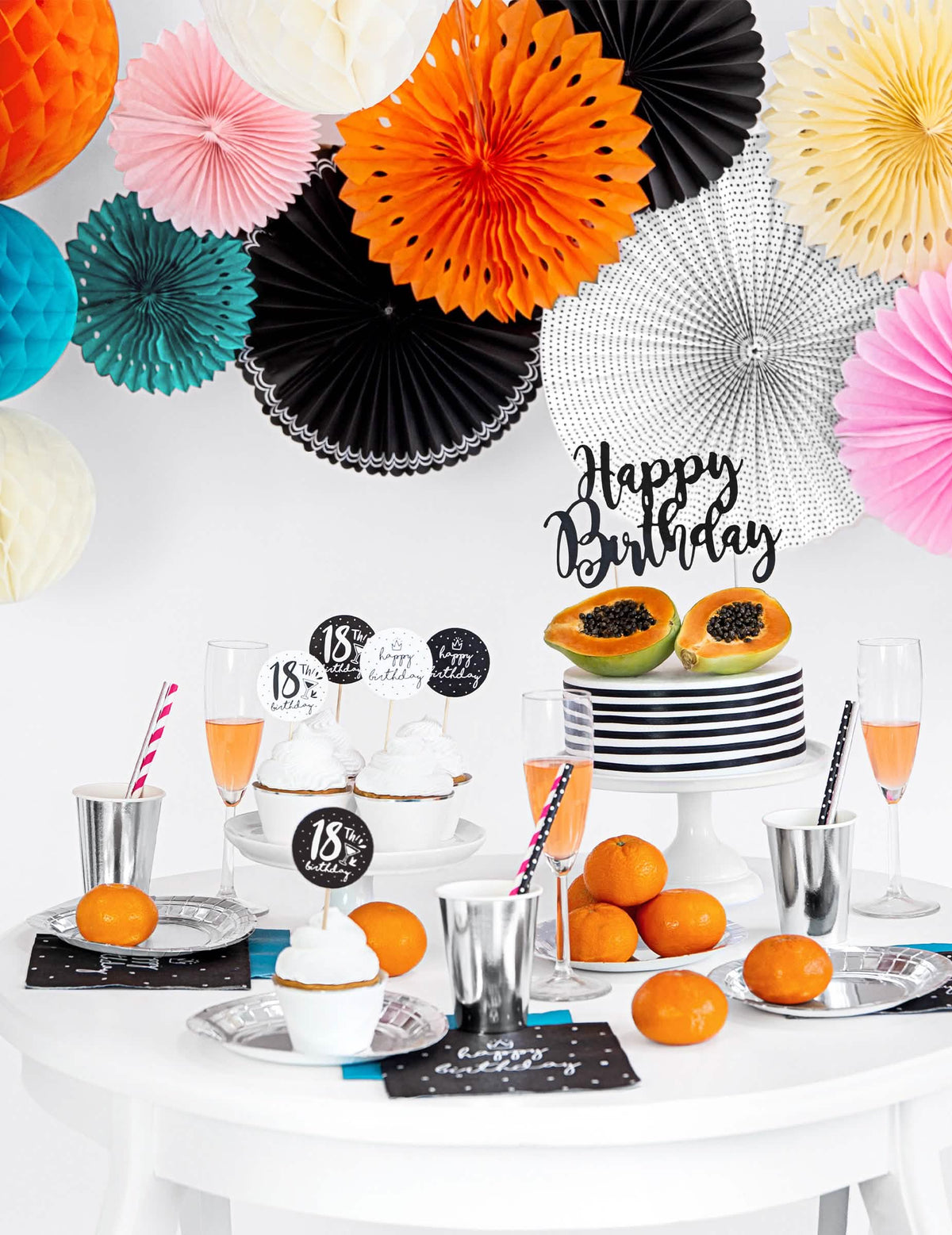 Mise en scène sur une table d'anniversaire des rosaces en papier pour décoration noires et blanches à motifs variés