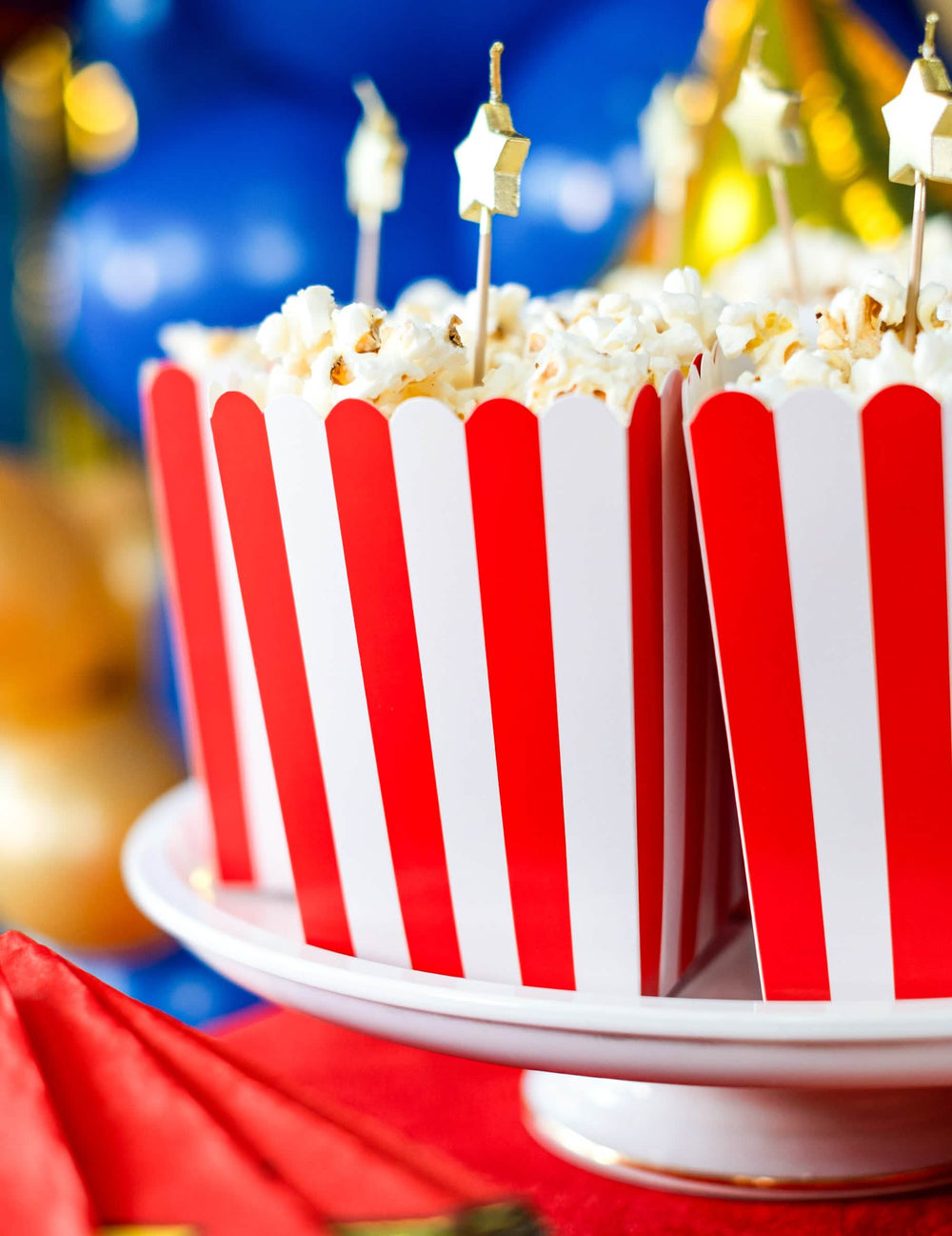 Lähikuva popcornista ja punaisten ja valkoisten pahvisten popcorn-laatikoiden kultaisista tikkuista