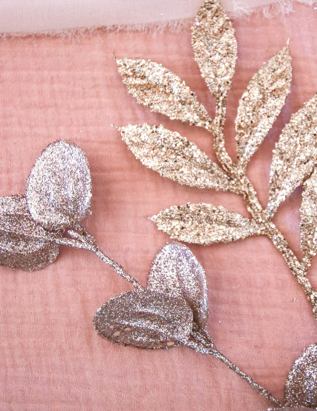 Détail du fini pailleté des branches d'eucalyptus pour décoration de fête rose gold givré à paillettes