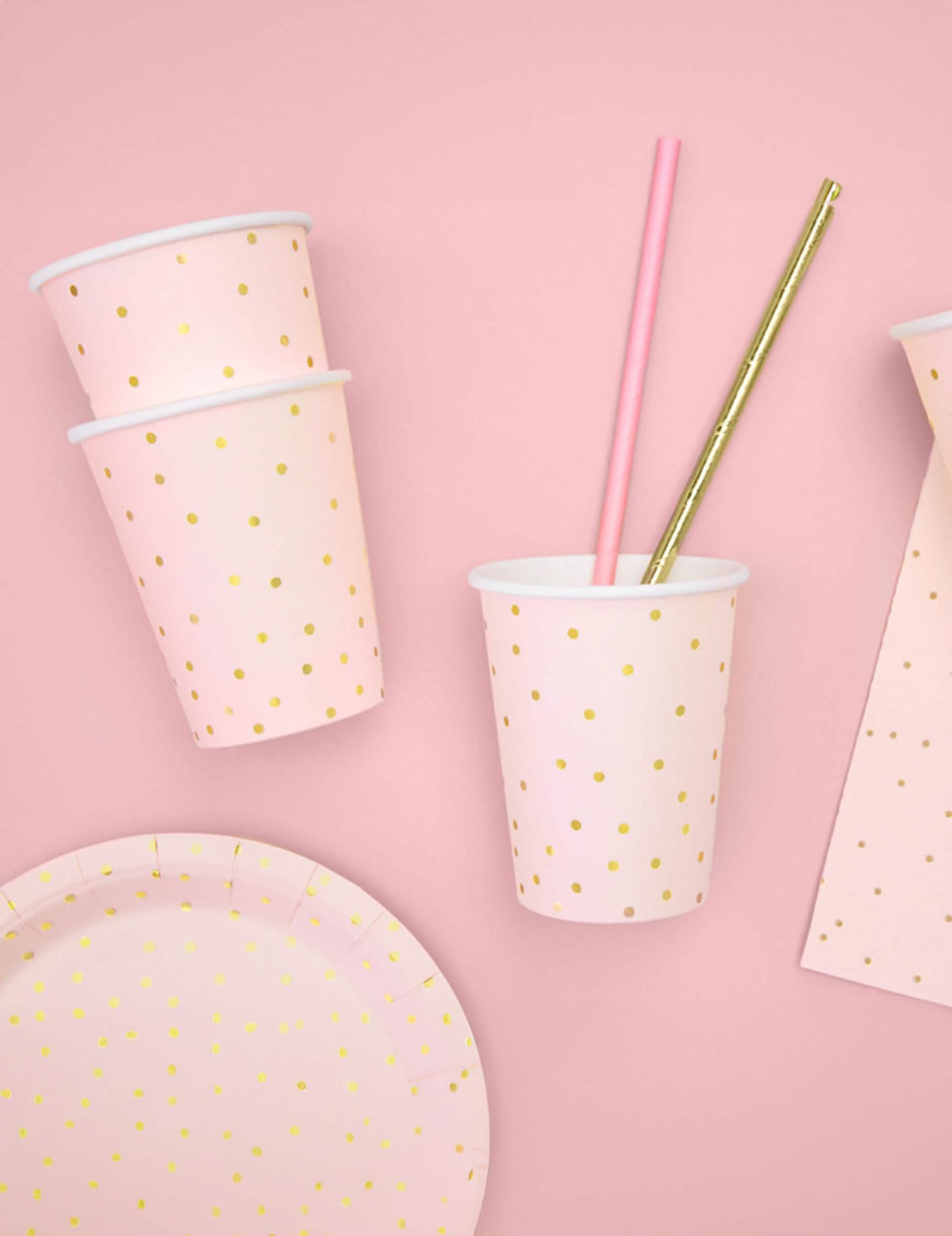 Vue avec assiette et pailles assorties des gobelets en carton rose pâle et pois dorés