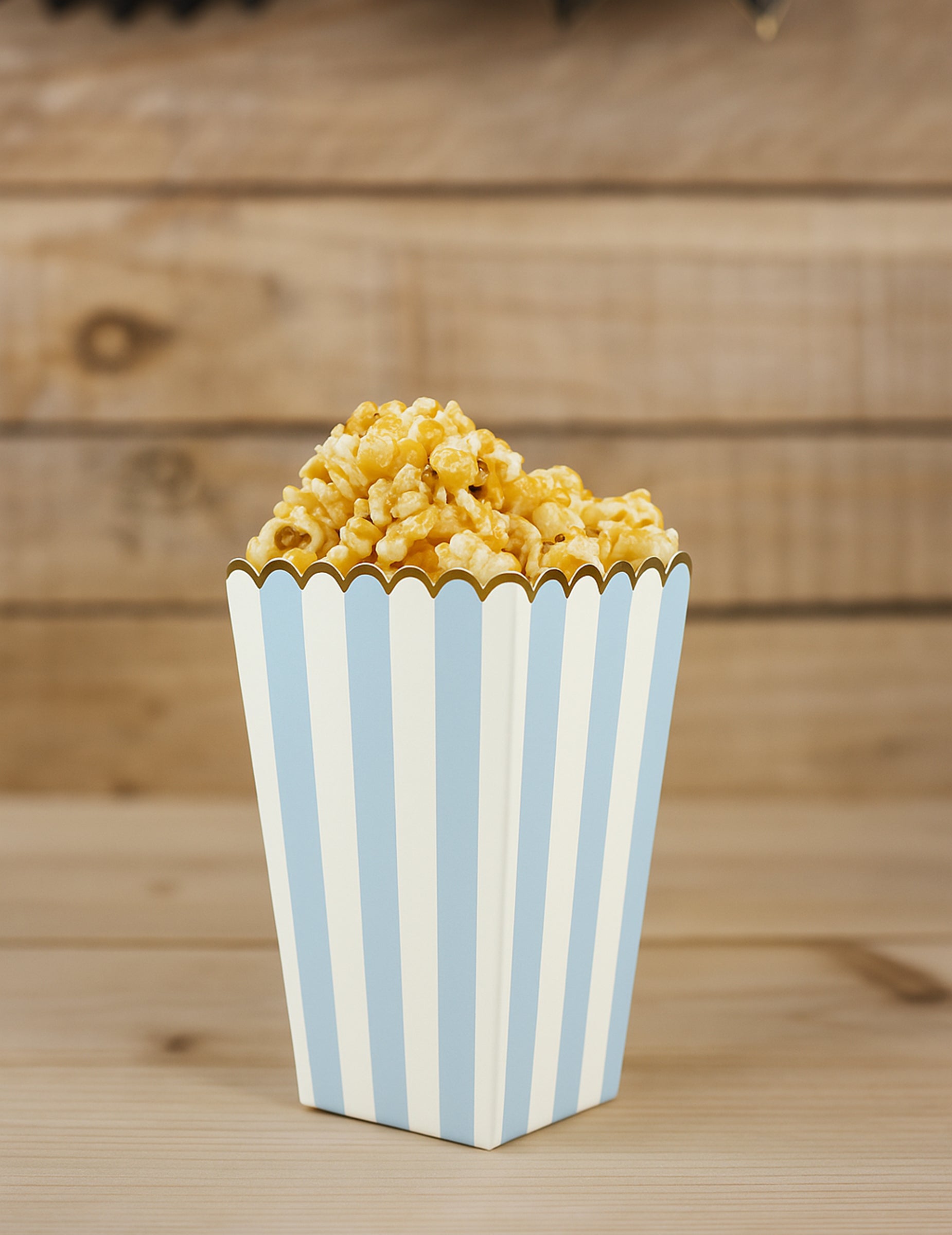 Vue d'une boîte remplie des boîtes à pop corn pour fête bleu pastel et or en carton rayé