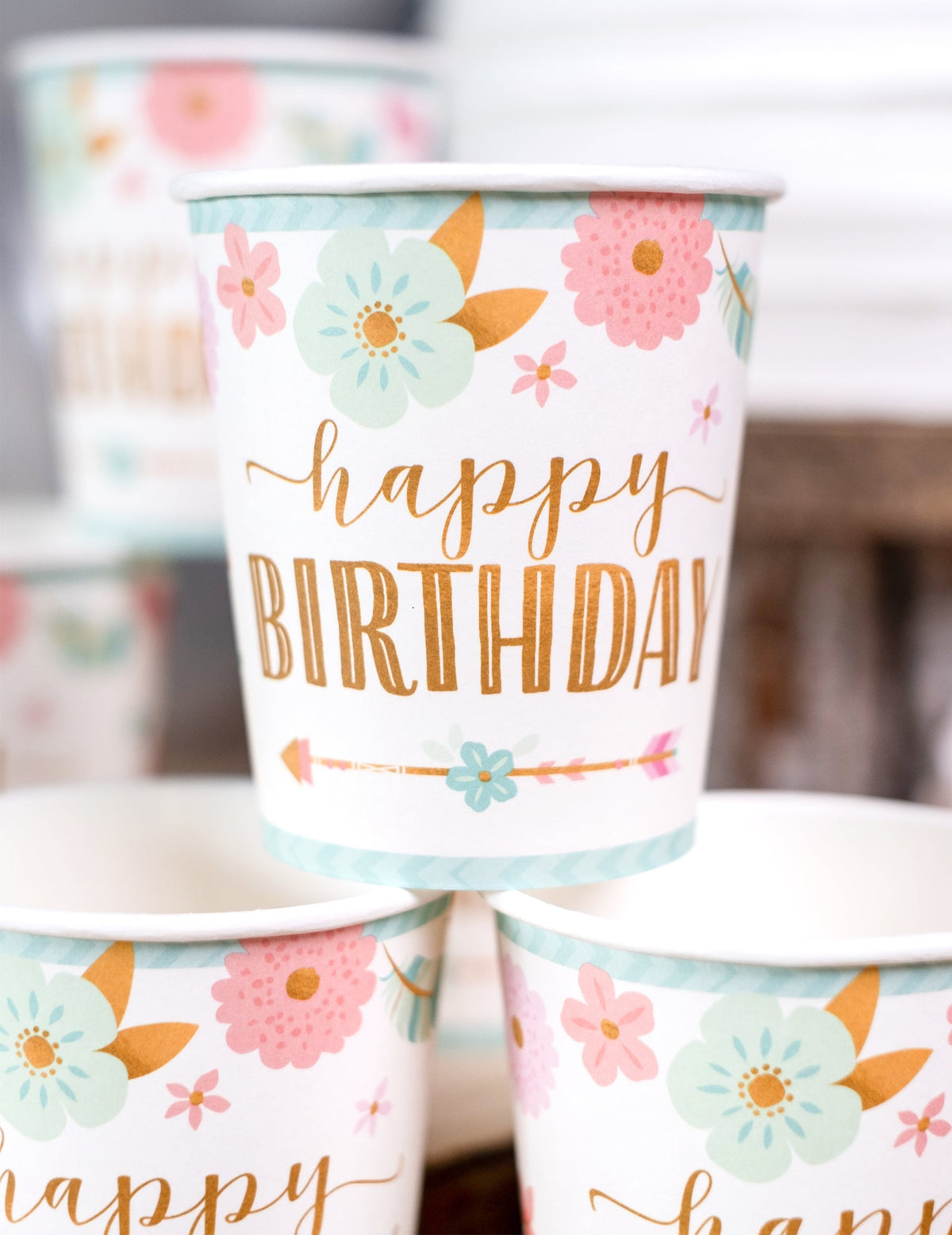 Gros plan sur l'imprimé floral et doré des gobelets en carton boho happy birthday