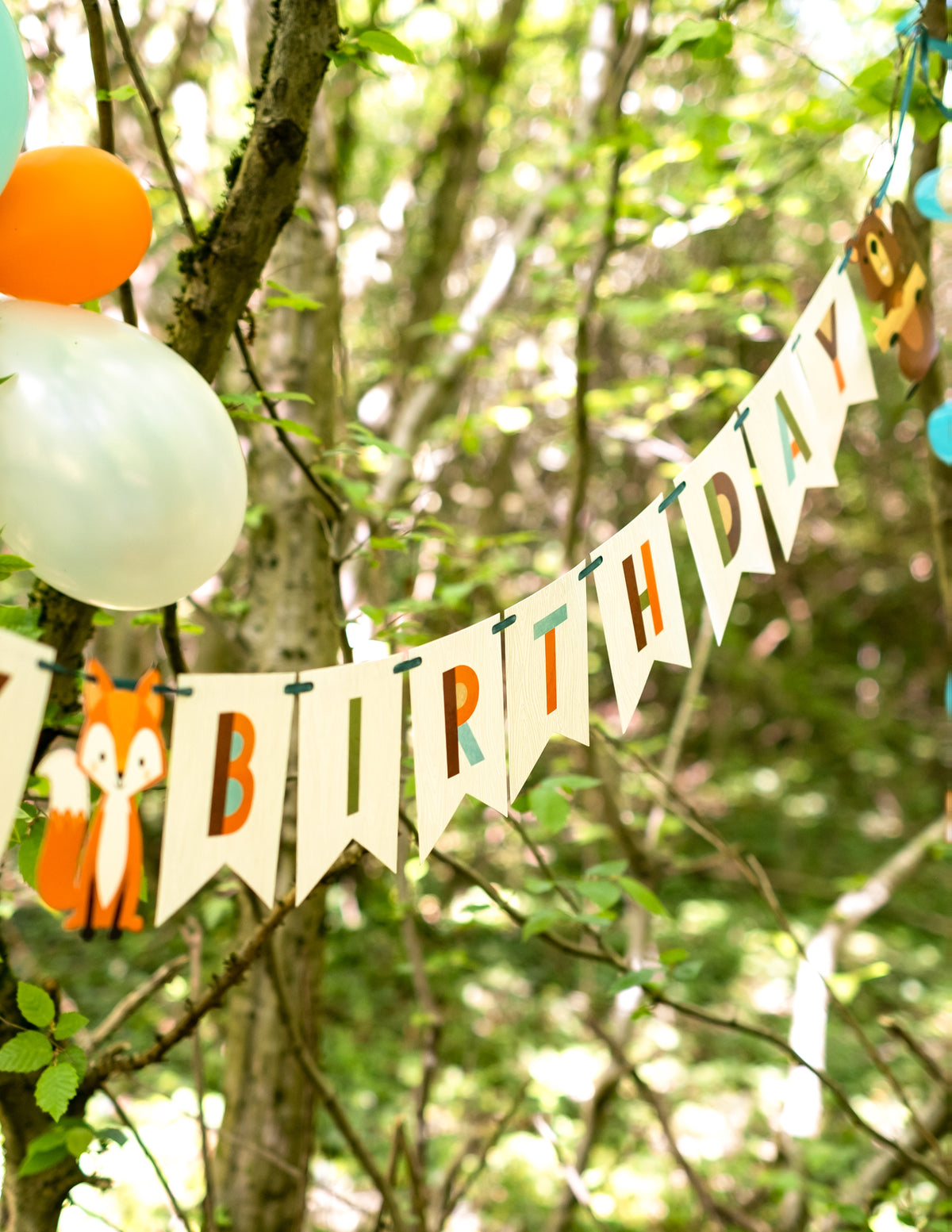 Mise en situation en extérieur de la bannière en carton happy birthday animaux de la forêt
