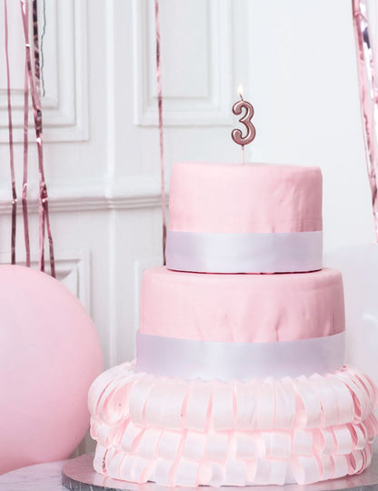 Mise en situation sur un gâteau de la bougie d'anniversaire chiffre 3 rose gold métallisée avec pic