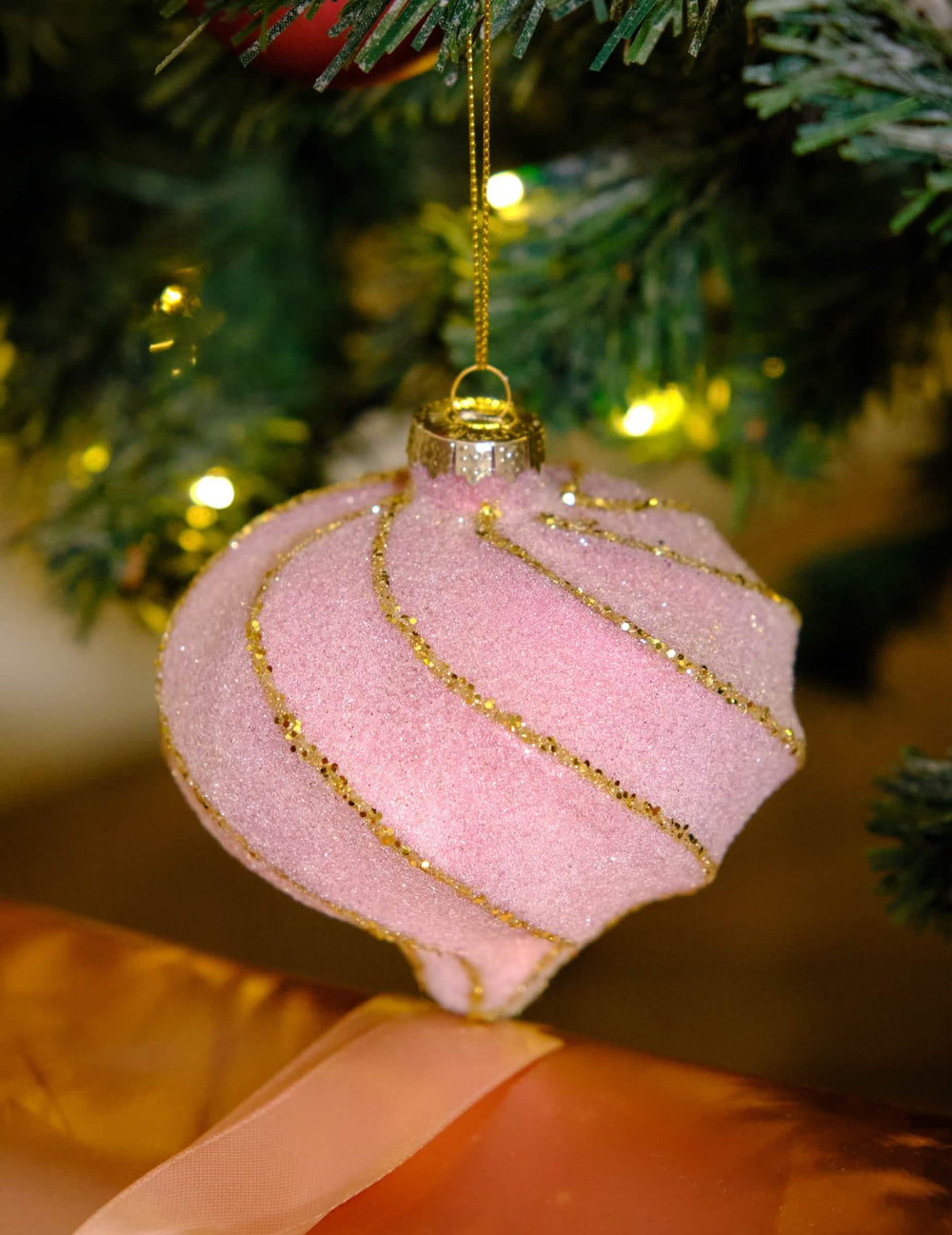 Gros plan sur la boule de noël forme goutte et spirales rose et or pailletée