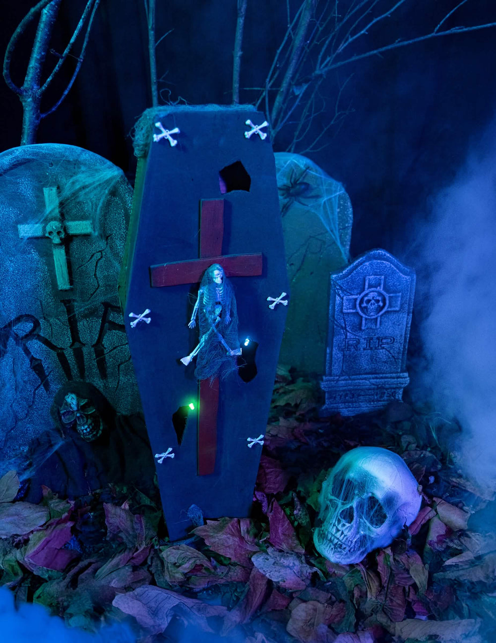 Asetelma hautausmaan lavasteessa, jossa on arkku, risti halloweenia varten