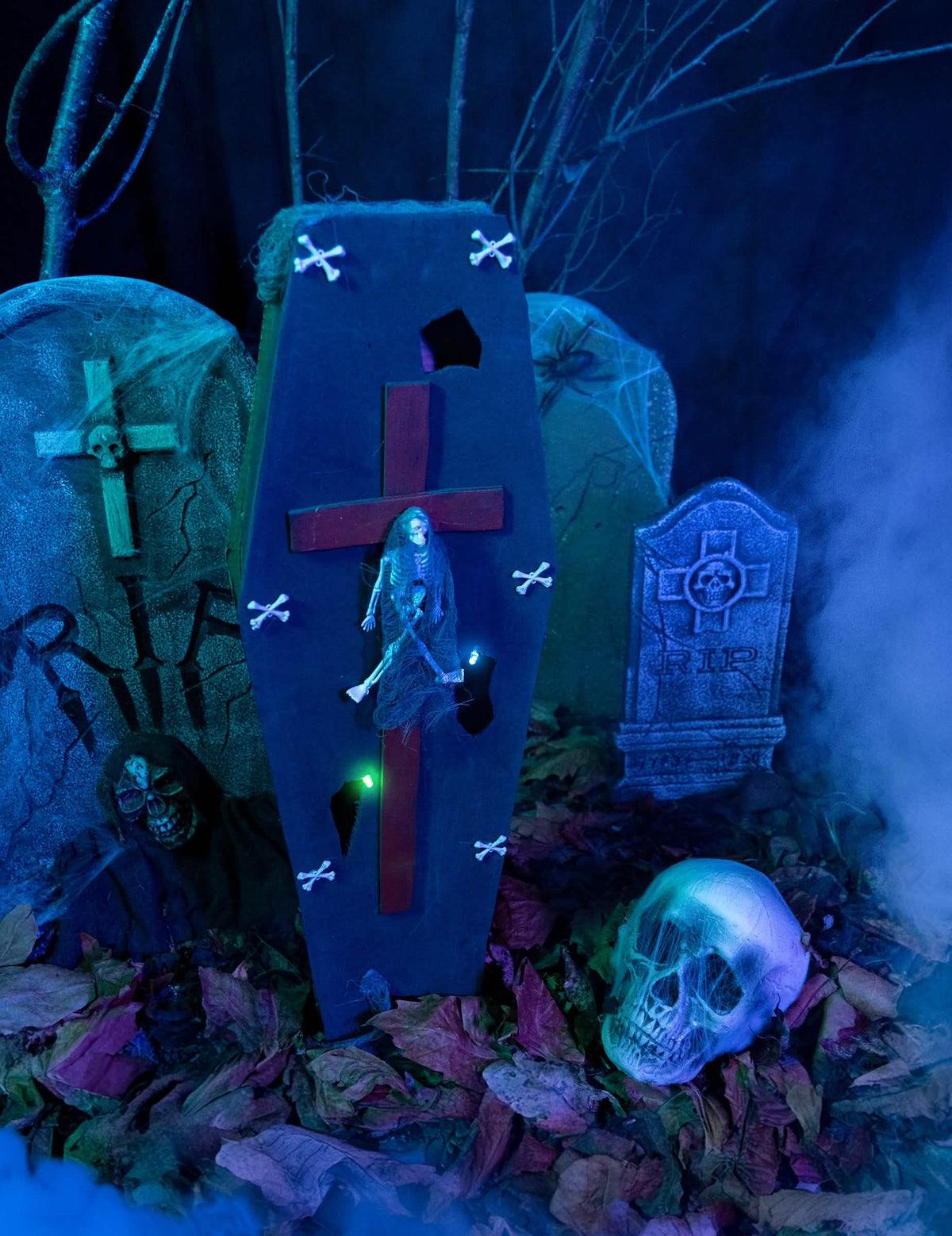 Asetelma hautausmaan lavasteessa, jossa on arkku, risti halloweenia varten