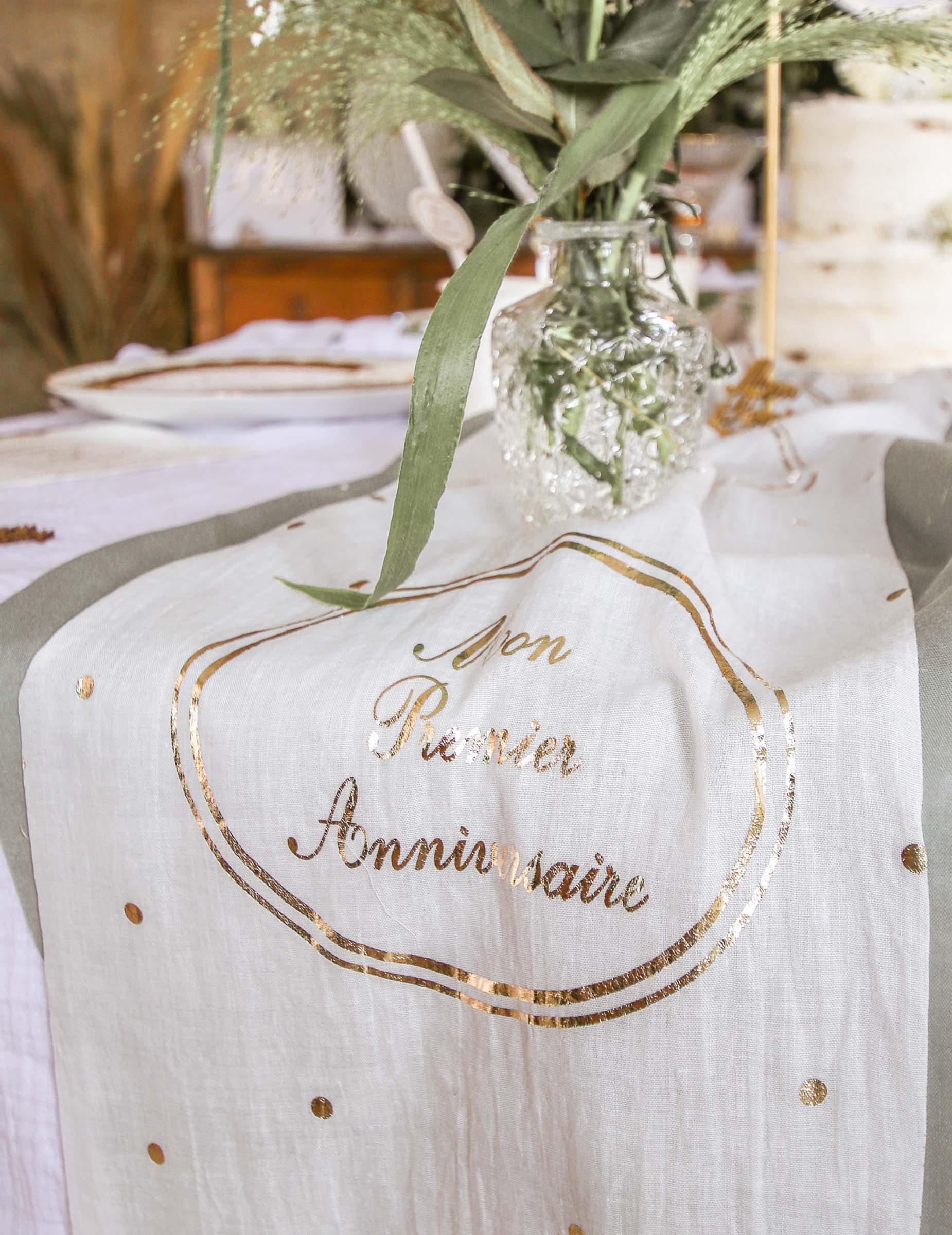 Détail de l'inscription dorée du chemin de table en gaze de coton Mon Premier Anniversaire
