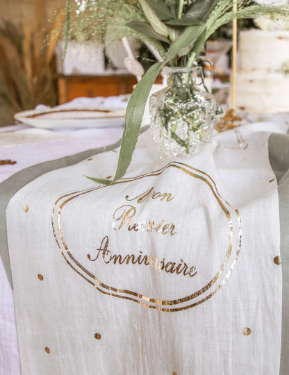 Détail de l'inscription dorée du chemin de table en gaze de coton Mon Premier Anniversaire