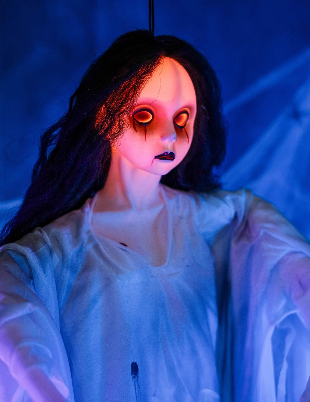 Lähikuva halloweeniin tarkoitetun riippuvan valkoisen naisen koristeen kasvoista, joilla on kirkkaat silmät
