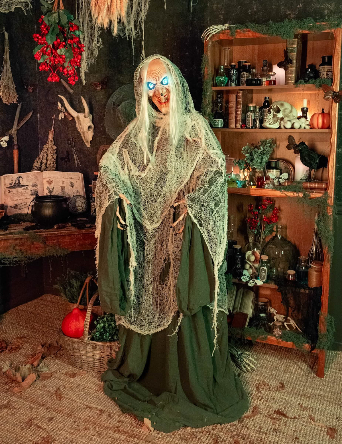 Mise en situation dans un décor d'Halloween de la décoration animée sonore et lumineuse Sorcière Andromeda
