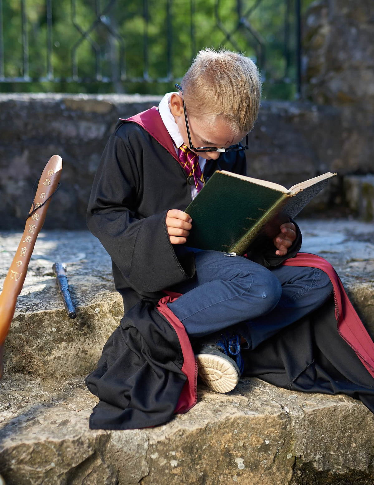 Mise en situation avec livre et baguette du déguisement Harry Potter™ pour enfant