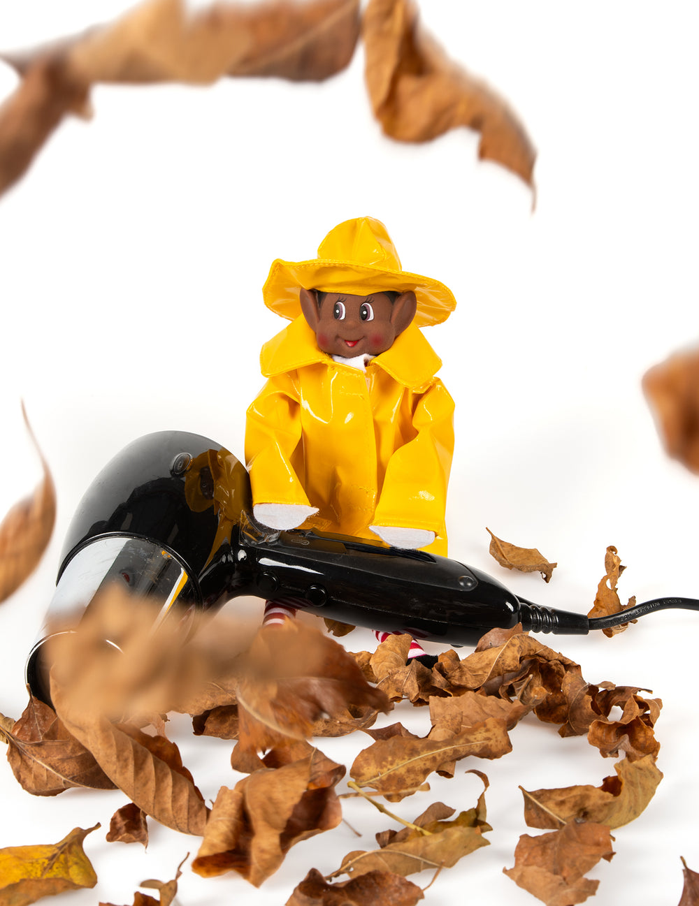 Mise en scène du déguisement imperméable de lutin farceur pour poupée avec sèche-cheveux et feuilles mortes