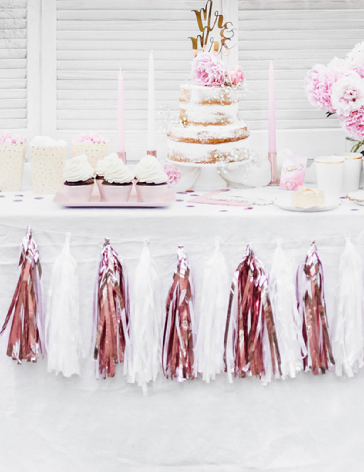 Mise en situation sur une table de la guirlande tassel 12 pompons pour décoration de fête rose gold métallisé