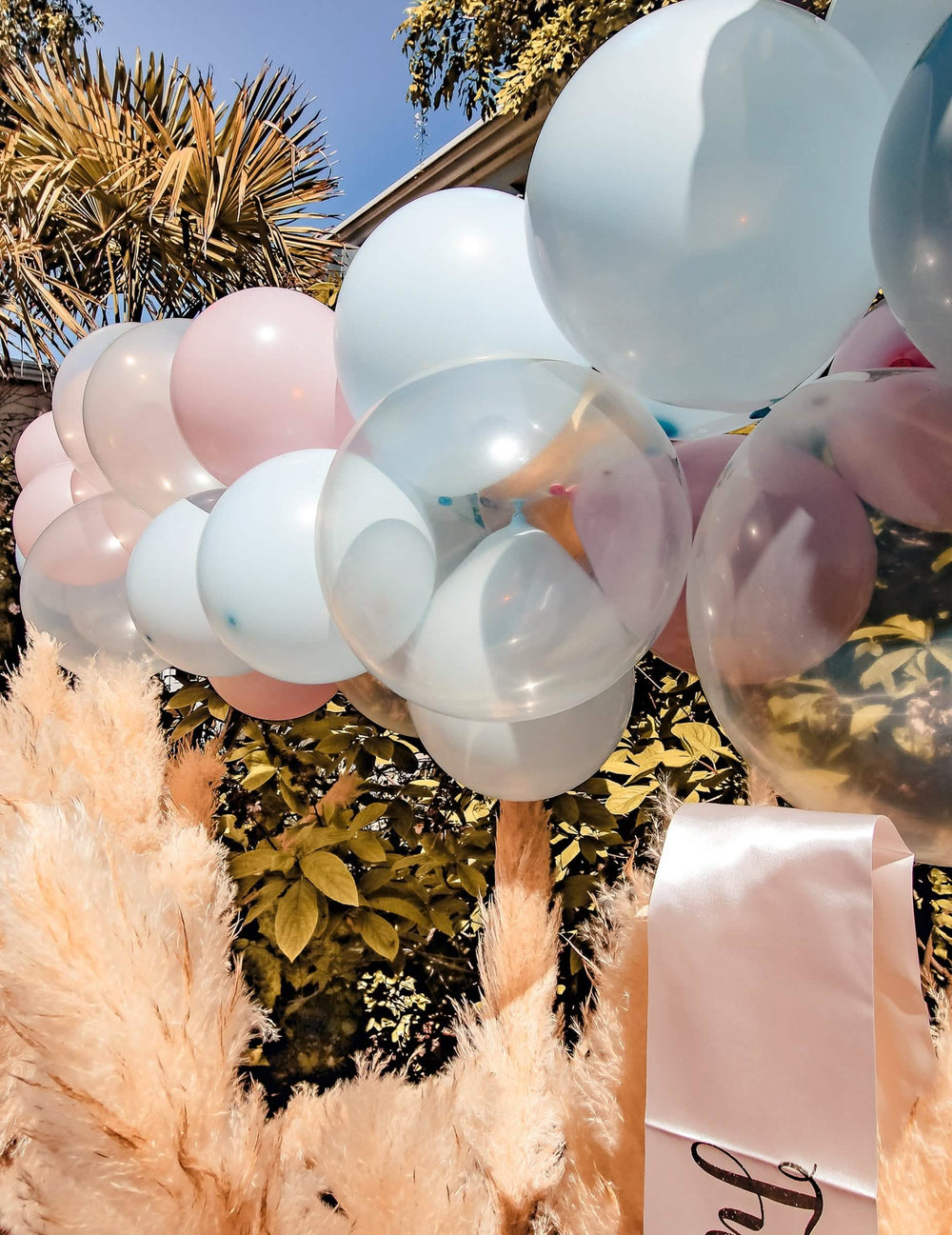 Lähikuva 58 ilmapallosta koostuvasta kaaripaketista gender reveal -juhliin, sininen, vaaleanpunainen, valkoinen ja kulta