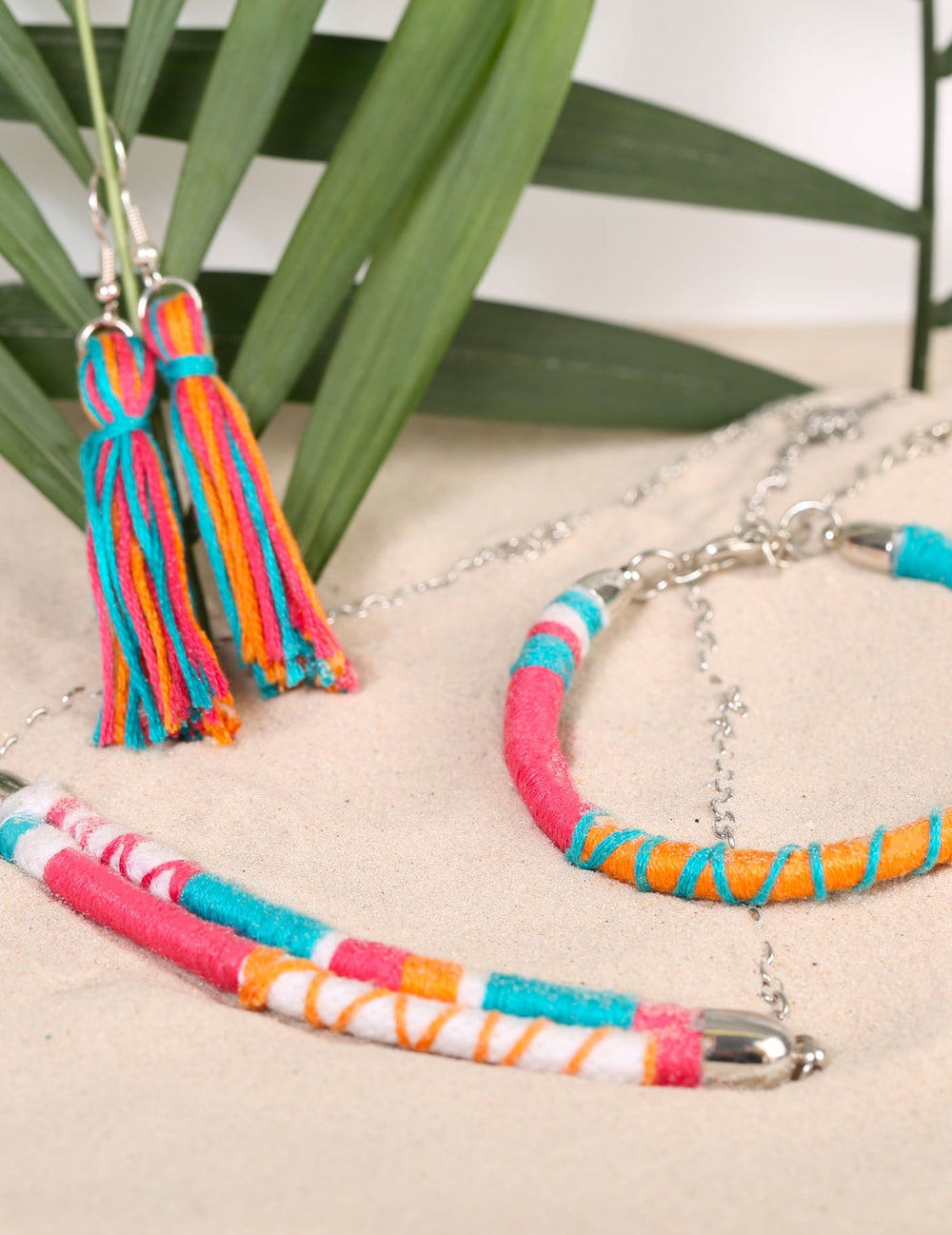 Détail des boucles d'oreilles à pompons et du bracelet du kit création de bijoux parure