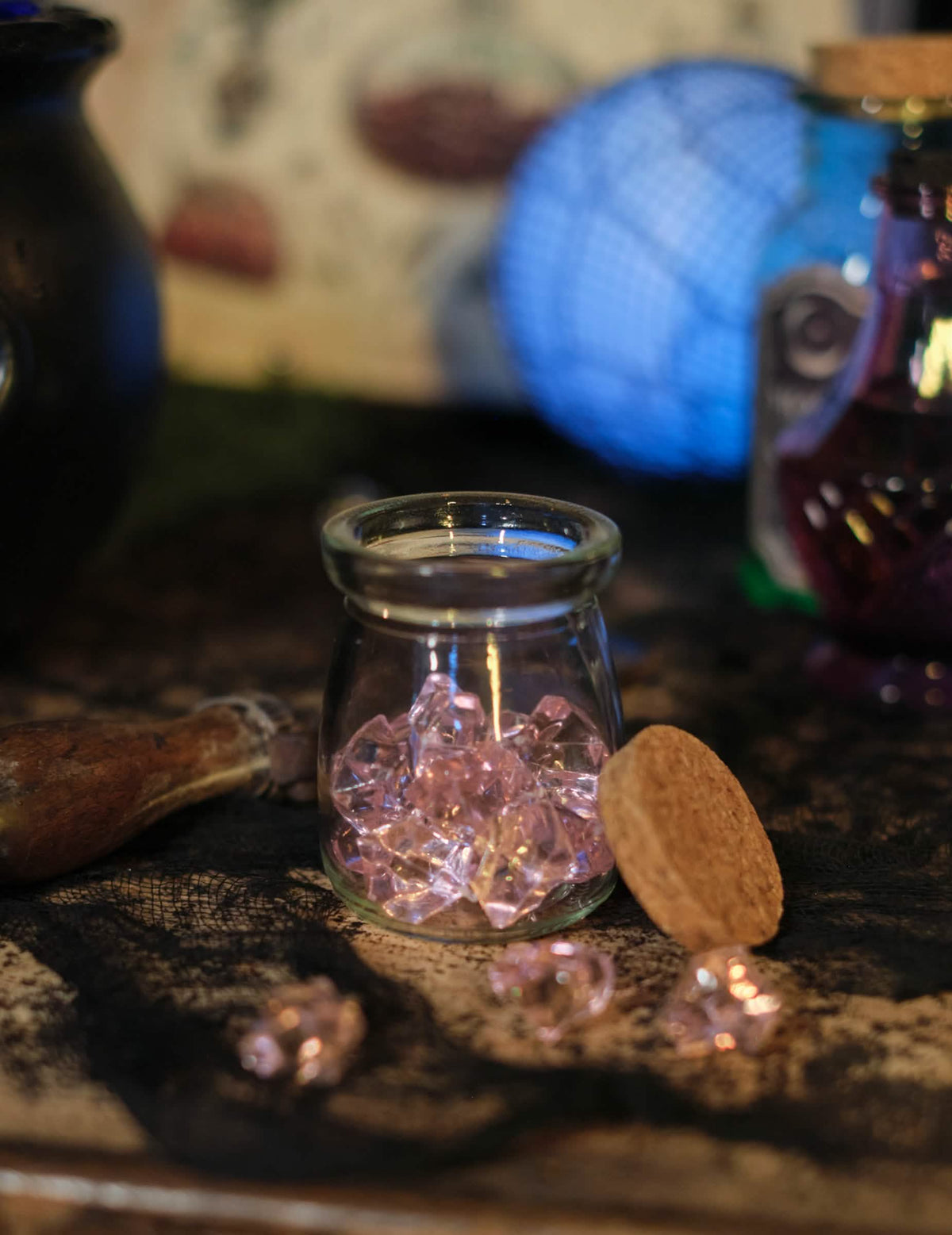 Détail des cristaux éparpillés devant le bocal des pierres effet cristal pour décoration de table rose