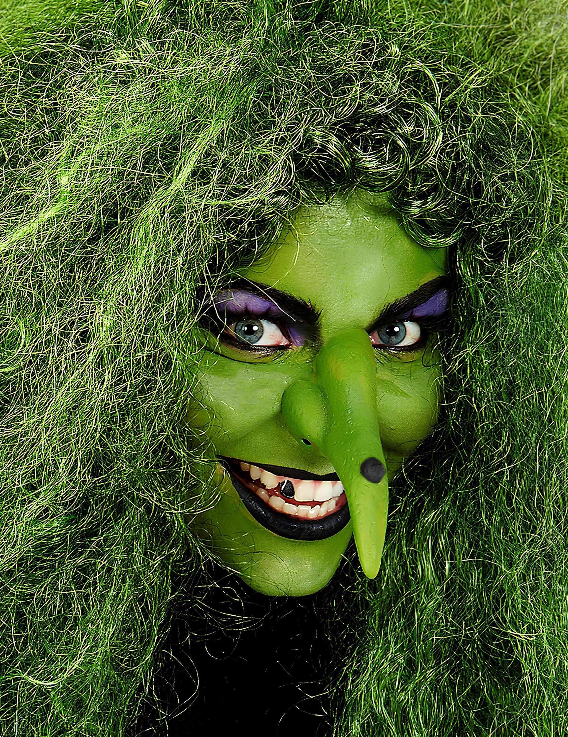 Gros plan sur le visage maquillé en sorcière du maquillage professionnel à l'eau pour visage et corps vert