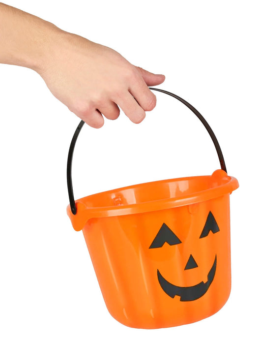 Kurpitsat-halloween-ämpärin kahvaa pitelevän käden yksityiskohta